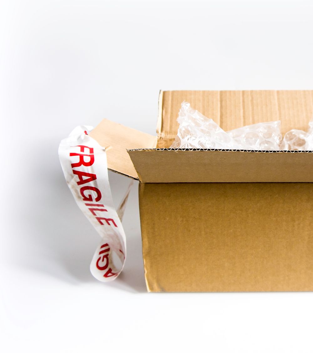 A moving box being packed and sealed with Fragile tape